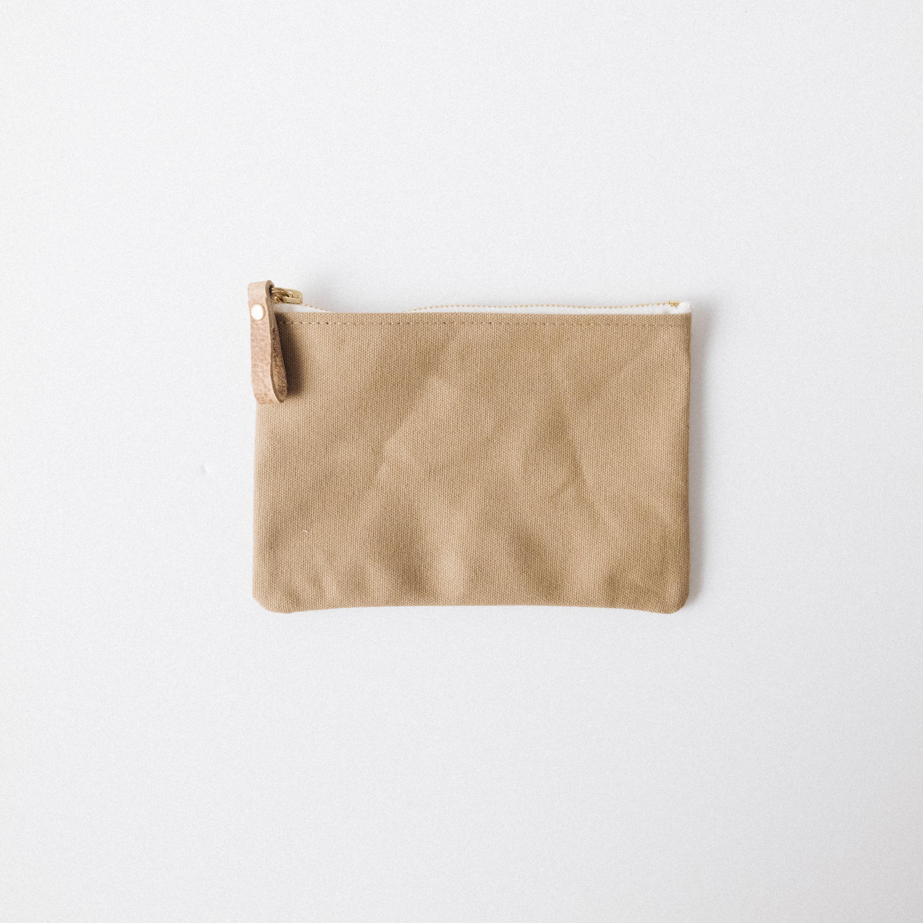 Handmade tan cotton canvas zip pouch with a solid brass zipper and durable leather pull for easy organization.