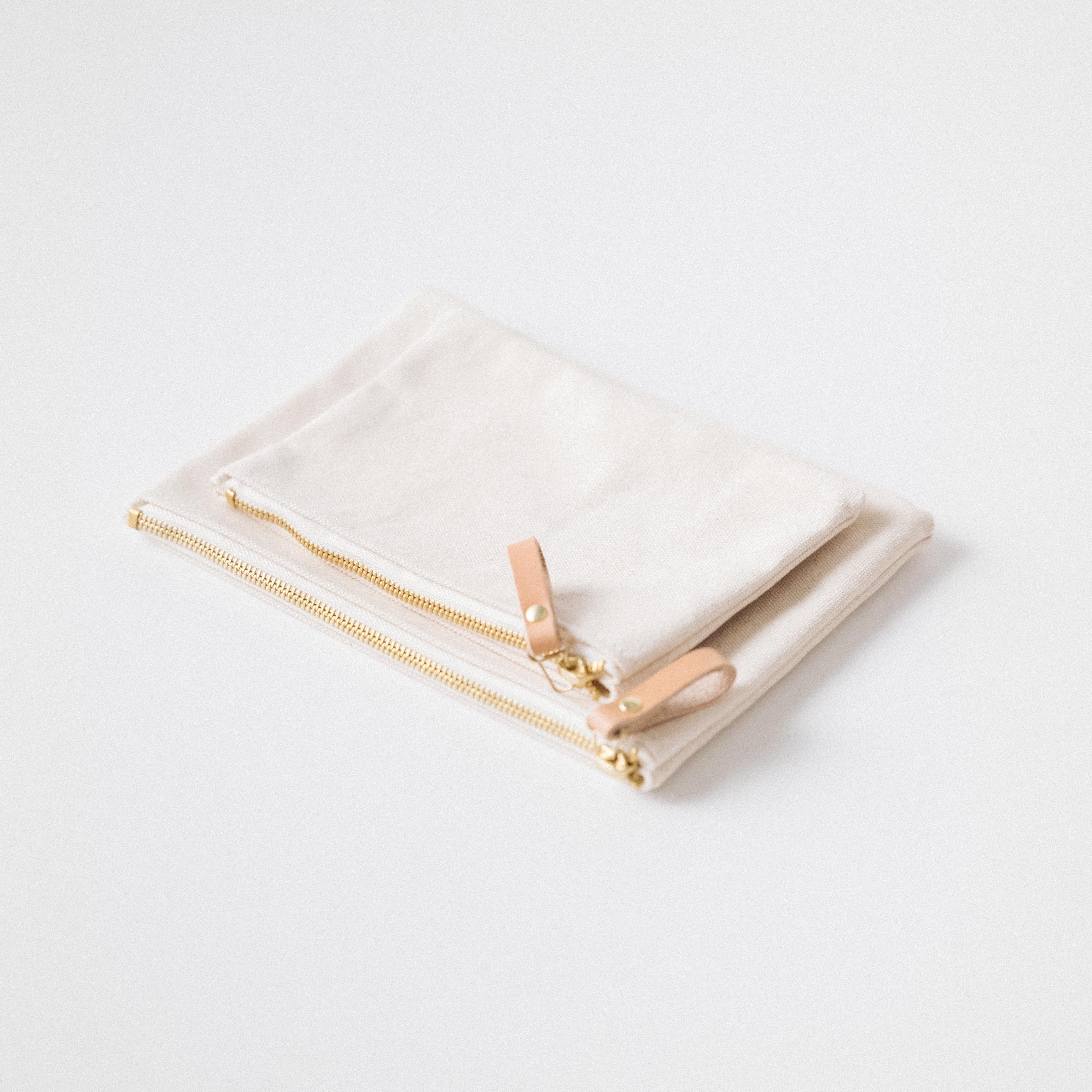 Two handmade heavyweight cotton canvas zip pouches with solid brass zippers and elegant leather pulls.