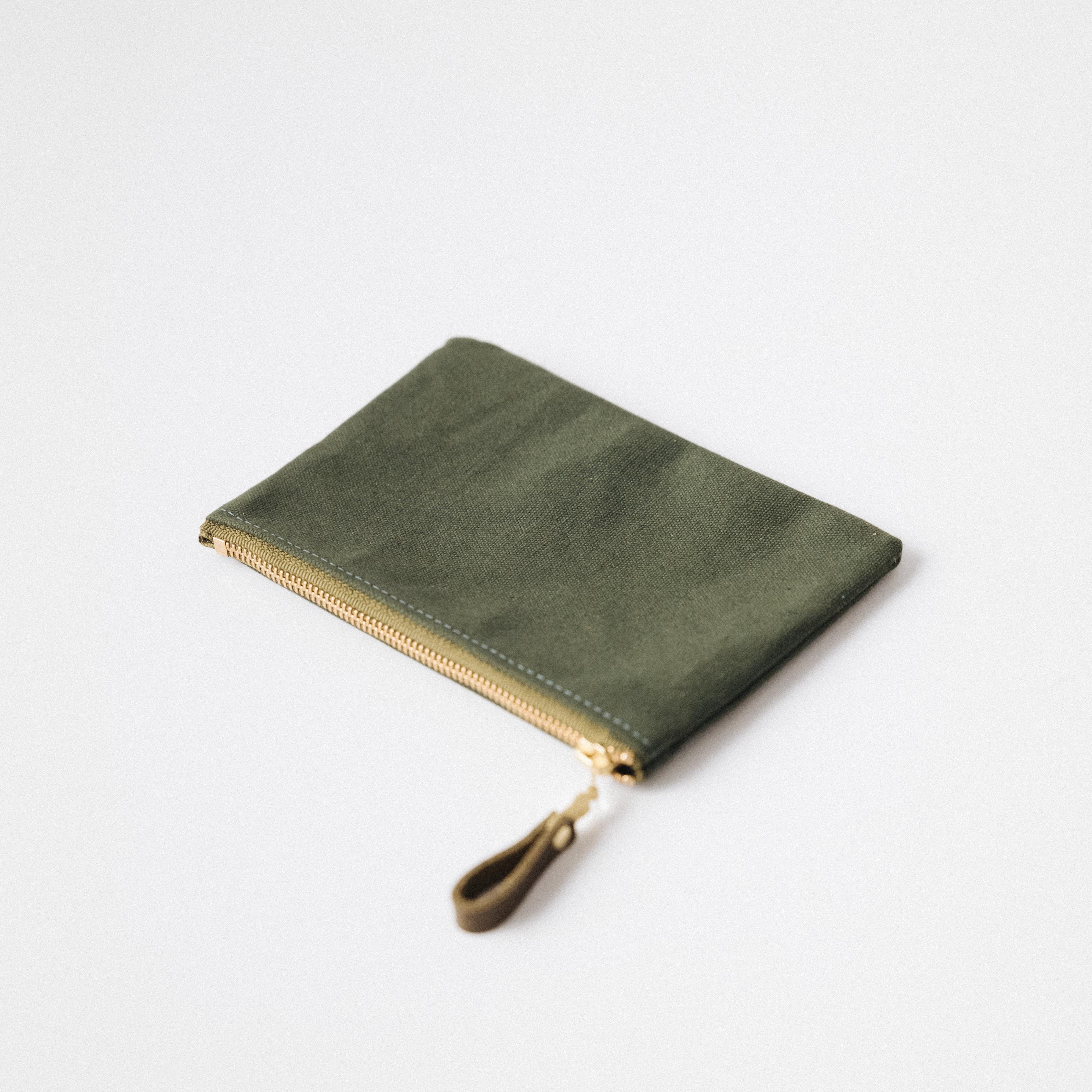Olive green heavyweight cotton canvas zip pouch with a solid brass zipper and leather pull for easy organization.
