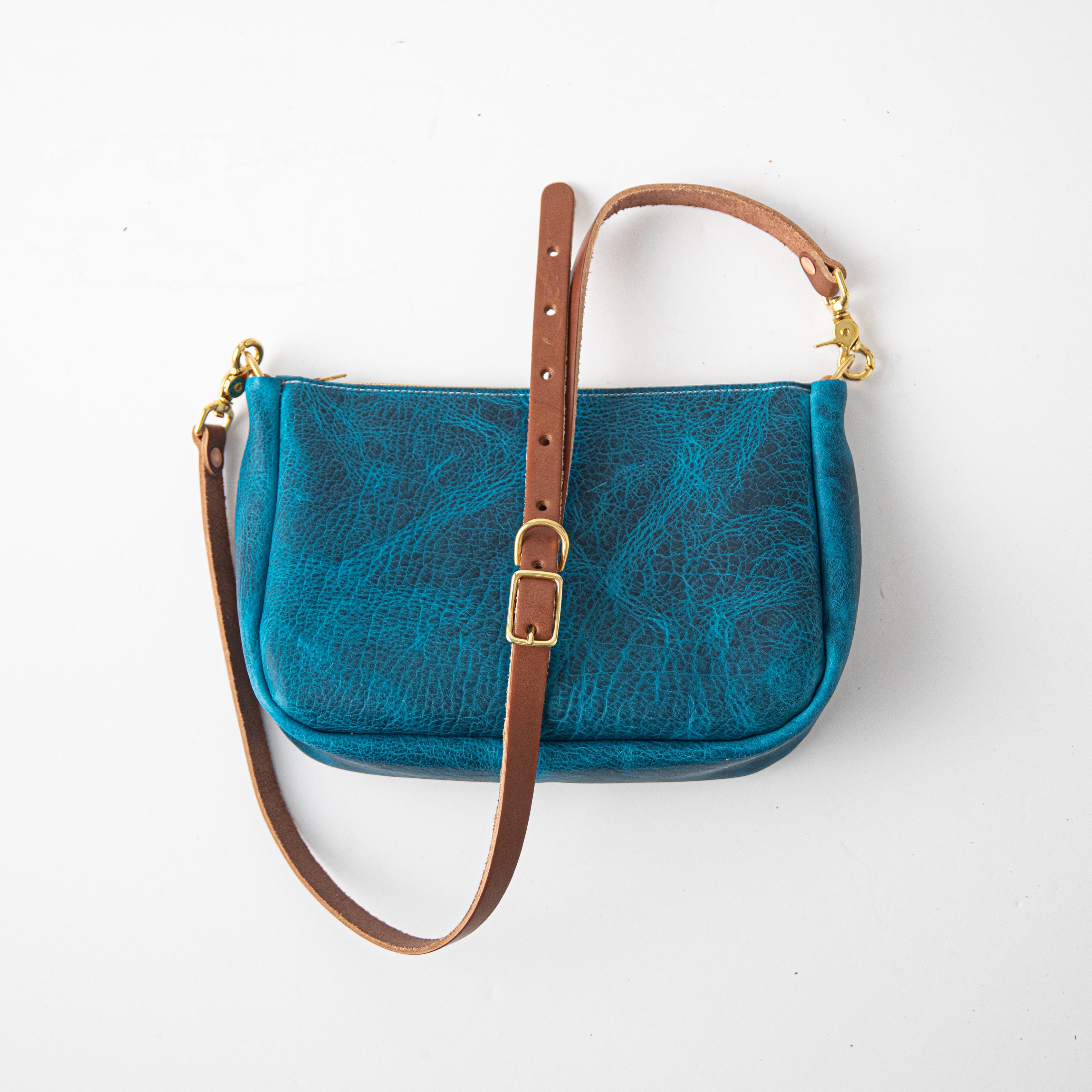 Petrol Blue Bison Crossbody Bag, handmade in USA from full-grain leather, with a brown adjustable strap and brass hardware.