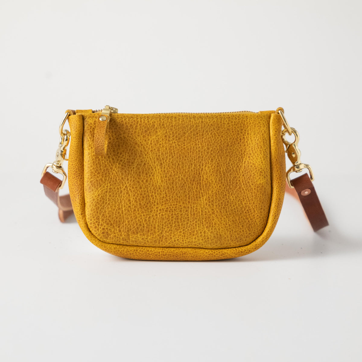 Yellow full-grain leather mini crossbody bag with a secure brass zipper and sturdy brass hardware.