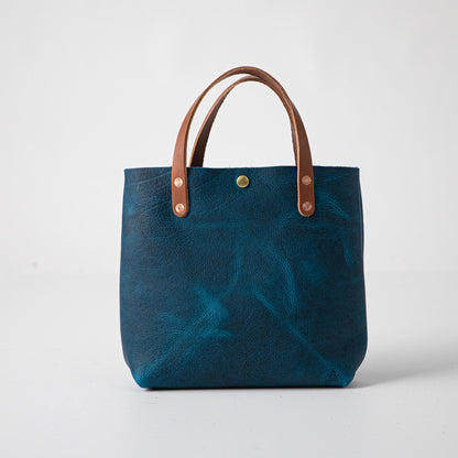 Petrol Blue Bison Mini Tote: vibrant blue full-grain leather, tan handles, and a single brass snap closure.