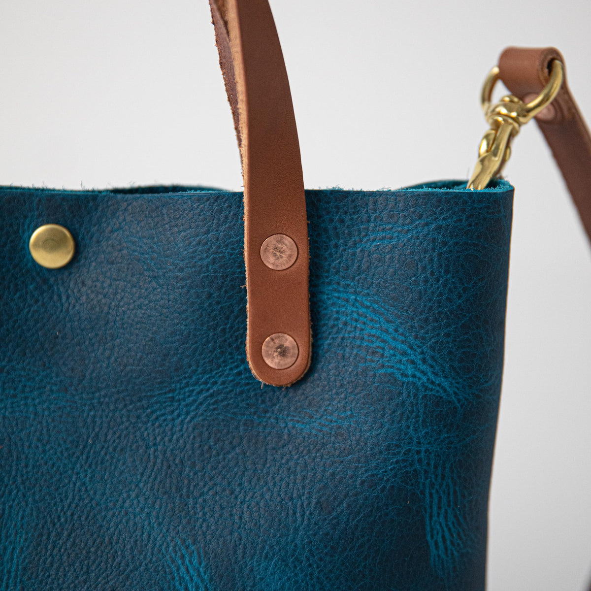 Close-up of a Petrol Blue Bison Mini Tote, showcasing its vibrant full-grain leather, Tan handles, and brass hardware.