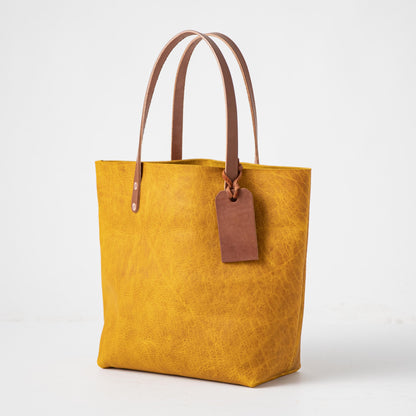 Handmade Yellow Bison leather tote bag with prominent grain, Tan handles, and a free customizable leather tag.