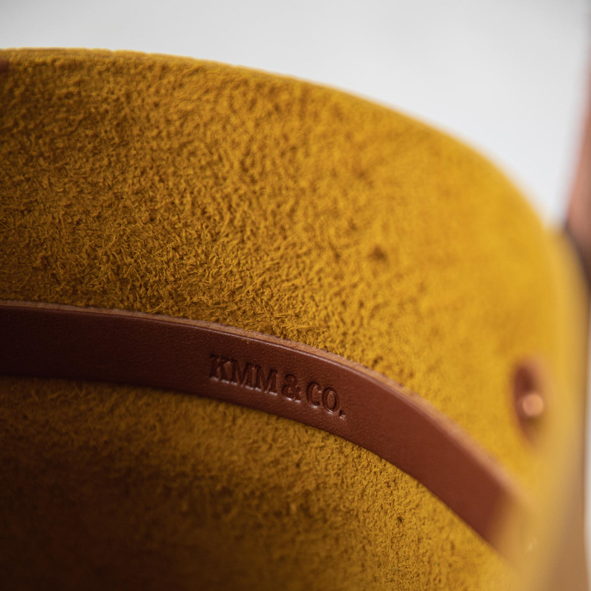 Close-up of the Yellow Bison Tote, showcasing its vibrant yellow leather with a prominent grain and soft temper. Tan leather strap with "KMM &amp; CO." embossed.