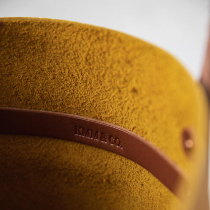 Close-up of the Yellow Bison Tote, showcasing its vibrant yellow leather with a prominent grain and soft temper. Tan leather strap with "KMM &amp; CO." embossed.