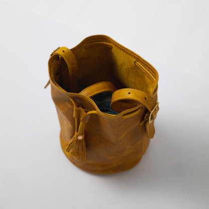 Vibrant Yellow Bison full-grain leather bucket bag with prominent grain, soft temper, and adjustable strap.