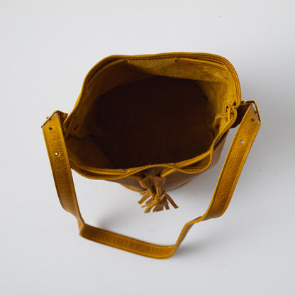 Vibrant Yellow Bison full-grain leather bucket bag with a prominent grain, soft temper, and tassel drawstring.