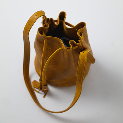 Vibrant Yellow Bison full-grain leather bucket bag with a soft temper, prominent grain, and adjustable strap.